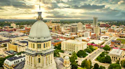 Aerial view of the Illinois State Capitol dome and Springfield skyline under a dramatic sunset