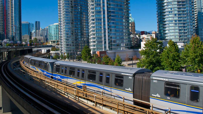 A TransLink SkyTrain traveling on an elevated guideway through downtown Vancouver.