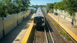 Marc A. Hermann | MTA A new MTA R211 subway train enters Broad Channel station on the elevated Rockaway line as part of the Rockaway Park Shuttle's rolling stock upgrade, with Jamaica Bay marshland and a distant skyline behind.