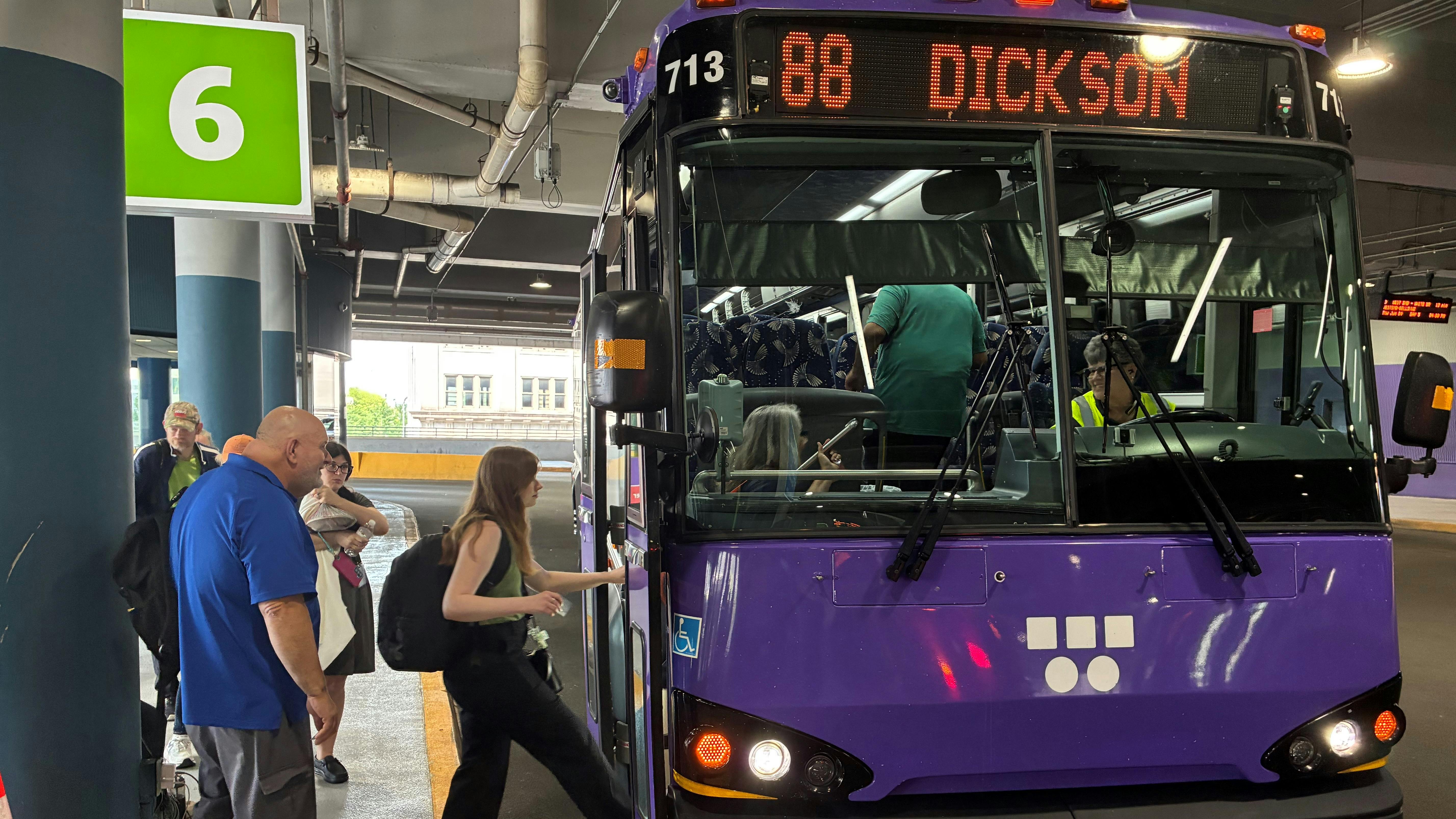 Riders board a purple WeGo Public Transit bus under a '6' sign.