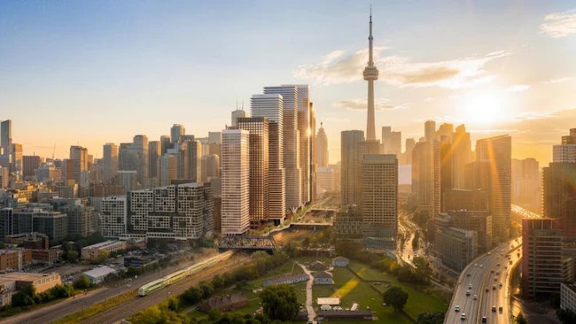 An aerial rendering of a mixed-use development proposed near Fort York in Toronto, Ontario, featuring several high-rise residential and commercial towers with warm terracotta-toned facades, surrounded by green space and transit infrastructure