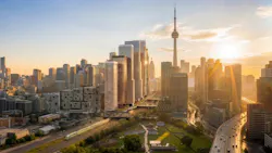 An aerial rendering of a mixed-use development proposed near Fort York in Toronto, Ontario, featuring several high-rise residential and commercial towers with warm terracotta-toned facades, surrounded by green space and transit infrastructure