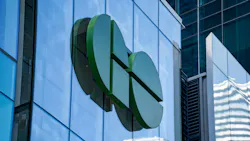 A large three-dimensional GO Transit logo mounted on the glass exterior of a modern office building, rendered in dark and light green tones against a blue-tinted glass curtain wall facade.