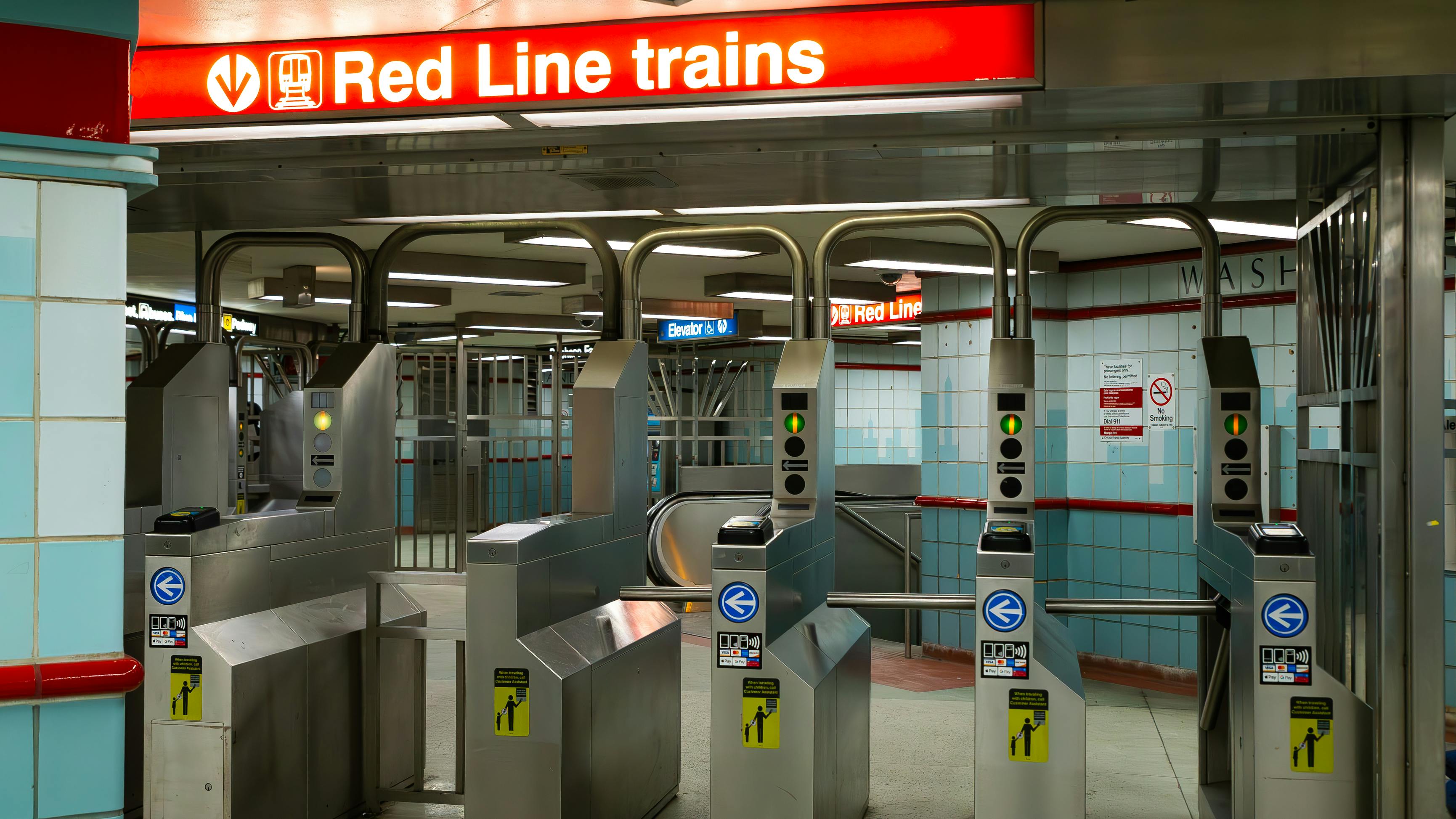 The fare gate area at a Chicago Transit Authority Red Line subway station, with a red overhead sign directing riders to Red Line trains and rows of turnstile-style fare gates equipped with contactless payment readers accepting Ventra, Apple Pay and Google Pay.