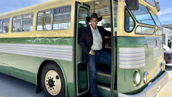 Marah Harris stands in the doorway of a 1948 twin motor coach wearing a black suit jacket and cowboy hat.