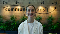 Natalie Lawrence stands smiling in front of a blurred Community Transit logo.