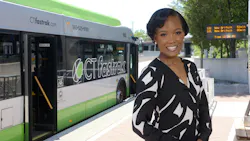 Trish L Chastanet, PMP, stands smiling in a blouse in front of a CT fastrak bus.