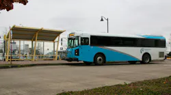 Cherriots Regional bus number 364 in a white and teal livery displays Route 80X on its destination board while pulling away from a yellow-framed bus shelter on an overcast day in the Salem, Oregon area.
