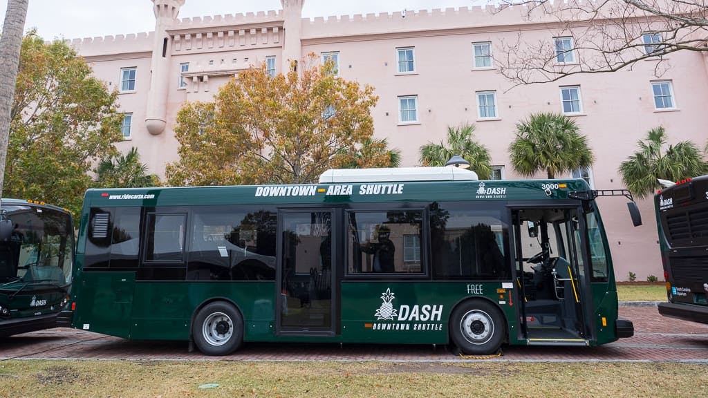 A downtown area shuttle sits parked betweeen two other buses.
