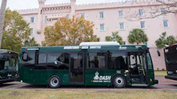 A downtown area shuttle sits parked betweeen two other buses.