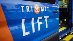 A close-up of a blue and orange TriMet LIFT paratransit vehicle's open side door, with the TriMet logo and 'LIFT' service name displayed prominently and a yellow grab bar and boarding step visible inside.