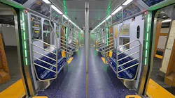 The interior of an empty MTA New York City Transit R211 subway car, featuring blue bench seating, stainless steel grab bars and poles, green LED accent lighting along the door frames, a blue speckled floor with yellow boarding arrows, and digital display screens, photographed at 145th Street station in June 2026.