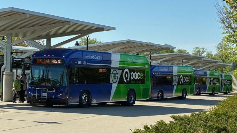 A row of Paces buses sit at the Joilet Transit Center under canopies.