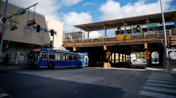 A blue Pace suburban bus stops beneath an elevated CTA rail line at the intersection of South Boulevard and Circle Avenue in Oak Park, Ill., with a '14 FT 0 IN' clearance sign visible under the bridge and traffic signals overhead.