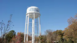The West Memphis, Arkansas water tower rises above a tree-lined park on a clear autumn day, bearing the city name prominently on its white spherical tank