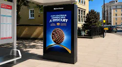 A bus shelter display integrated into the side of the structure displays an ad.