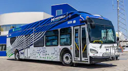 Montebello Bus Lines hydrogen fuel cell bus number 2039 in a bold blue, white, and gray wave livery with molecular chain graphics and a CH2 hydrogen fuel designation on the roof, parked in front of a hydrogen fueling facility on a clear day in Montebello, Calif.