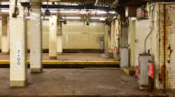 Empty New York City subway platform at the Chambers Street station, with white tile columns, a station wall marked 'Chambers St,' ceiling-mounted security cameras, and visible wear and rust along the walls.