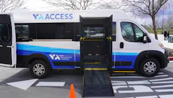 A Santa Clara Valley Transportation Authority ACCESS Paratransit van in white and blue livery with its side door open and ADA wheelchair ramp deployed, parked in a transit facility lot with an orange safety cone placed at the base of the ramp.