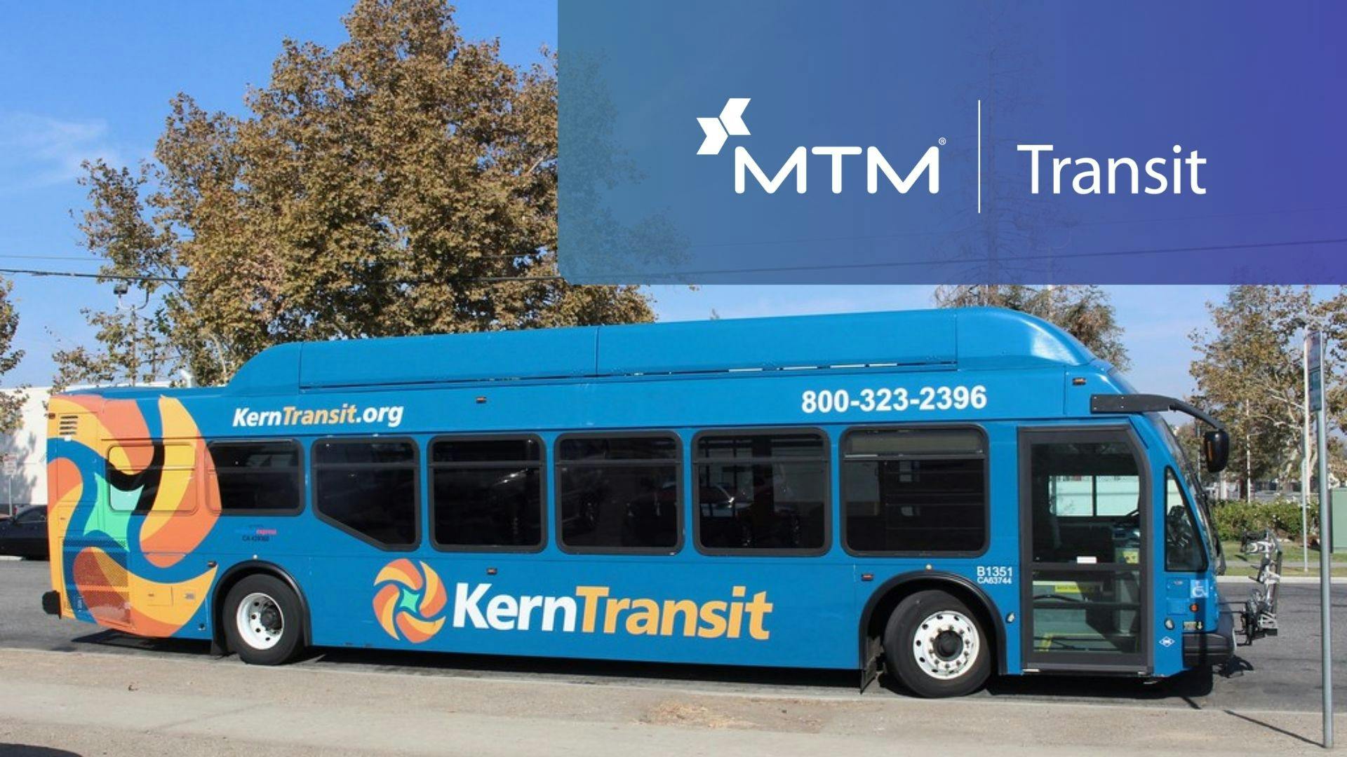 A blue Kern Transit bus parked on a street, featuring a colorful abstract wrap design, the agency's logo and website, and a promotional MTM Transit banner overlaid in the upper right corner.
