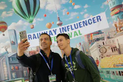 two people take a selfie in front of a backdrop that says railway influencer fest