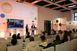 two people stand on stage with InnoTrans campus branding behind them as they talk to students in the audience