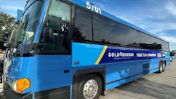 Gold Runner motorcoach bus number 5701 in a bright blue livery with a navy and yellow stripe displaying 'Gold Runner — Your Train Connection — Connecting You to California' branding along with Capitol Corridor and RARA logos, parked in a transit lot under a partly cloudy sky.