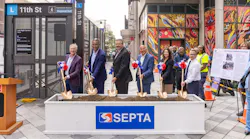 SEPTA officials pose with gold ceremonial shovels at a groundbreaking event for ADA improvements at the 11th Street 'L' station, standing behind a soil-filled planter bearing the SEPTA logo with the station entrance and a colorful mural in the background.
