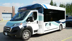 A Rhode Island Public Transit Authority (RIPTA) Model 1 Frontrunner van number 22565 in a white, navy and teal wave livery displaying 'Transit Authority' on its destination board, parked on a brick surface outside a transit facility with the RIPTA logo, RIPTA.com website and phone number visible on the side.