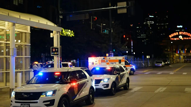 Multiple Transit Police vehicles and an ambulance with emergency lights activated respond to an incident near a station at night, with the illuminated Union Station sign visible in the background.