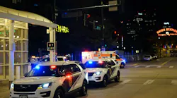 Multiple Transit Police vehicles and an ambulance with emergency lights activated respond to an incident near a station at night, with the illuminated Union Station sign visible in the background.