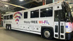 A white NJ Transit motorcoach, numbered 19132, parked inside a maintenance garage, featuring a 'Sit back. Relax. Enjoy FREE Wi-Fi.' ad wrap along its side.