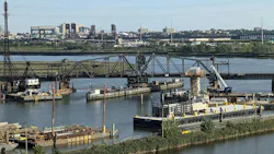 A representative photo of a rail bridge and surrounding waterway construction site, used to illustrate the Portal North Bridge project's second cutover for its final track, with barges, cranes, and the Newark, New Jersey skyline visible in the background.