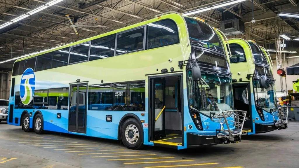 Two double-decker buses in green and blue livery, marked with the STA logo, parked inside a maintenance facility with front doors open and wheelchair ramps extended.