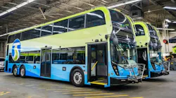 Two double-decker buses in green and blue livery, marked with the STA logo, parked inside a maintenance facility with front doors open and wheelchair ramps extended.