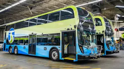 Two double-decker buses in green and blue livery, marked with the STA logo, parked inside a maintenance facility with front doors open and wheelchair ramps extended.