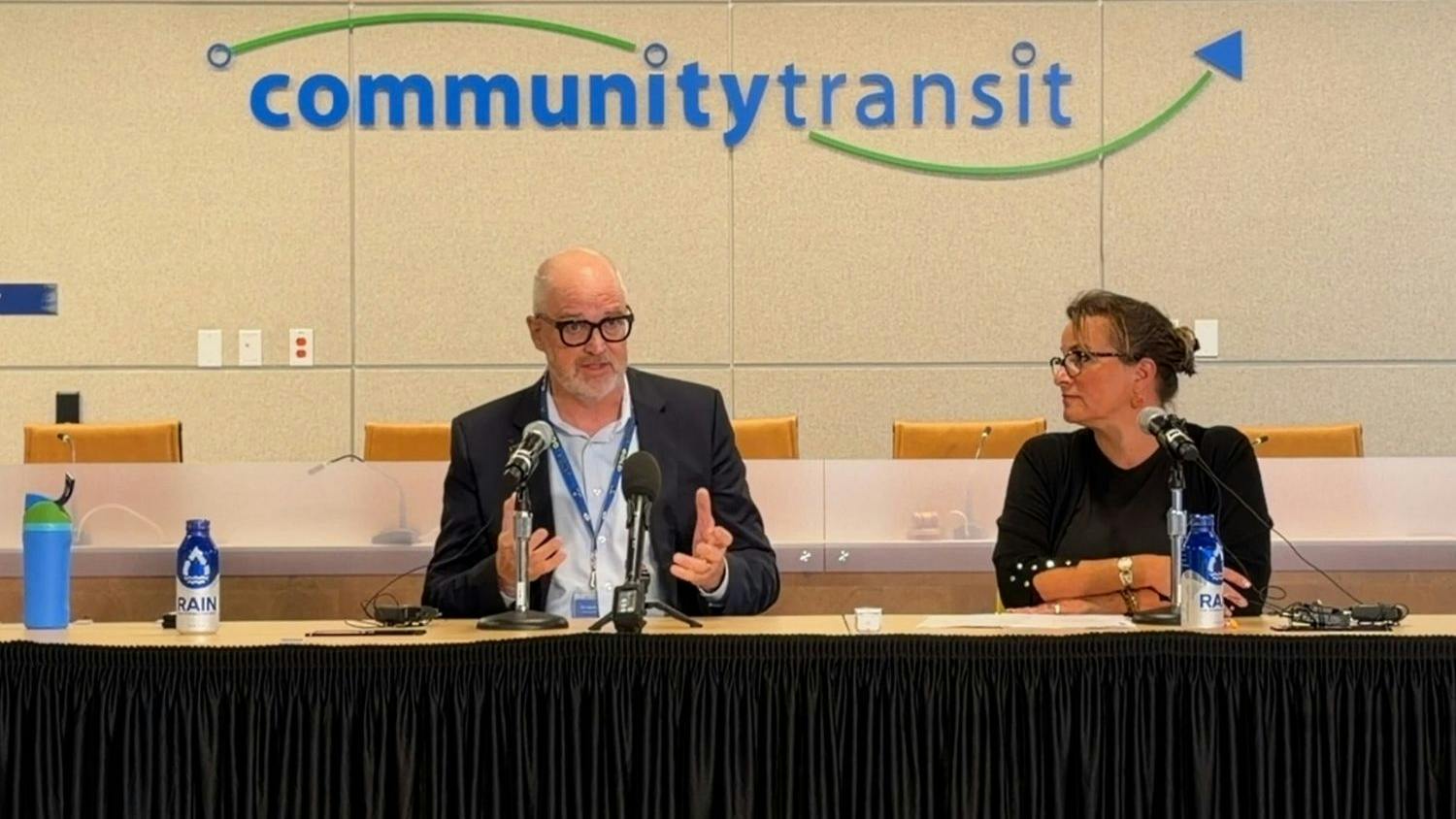 Community Transit CEO Ric Ilgenfritz and Everett Mayor Cassie Franklin speak at a press conference table in front of the Community Transit logo, announcing details of a proposed Interlocal Agreement