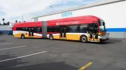 A red, white and yellow Long Beach Transit articulated bus, built by Complete Coach Works, parked outside the manufacturer's facility.