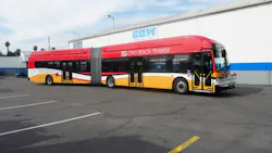 A red, white and yellow Long Beach Transit articulated bus, built by Complete Coach Works, parked outside the manufacturer's facility.
