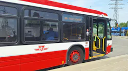 A TTC bus, numbered 3365 and signed '66 Prince Edward,' stands with its doors open at a curb, showing the agency's logo and priority seating signage, with a streetcar and power transmission towers visible in the background.