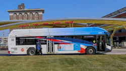 A GCRTA 'Cleaner Air Express' bus, unit 3358, is parked at a transit center in Cleveland with a passenger boarding, under a canopy structure and blue sky.