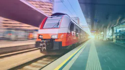 A red, white and gray electric passenger train speeds into a station with motion blur, passing a platform with a yellow safety line and tactile paving under a stylized teal and purple color grade.