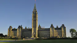 Canada’s Parliament Hill Centre Block and Peace Tower under a clear blue sky, viewed from the lawn.