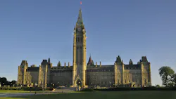 Canada’s Parliament Hill Centre Block and Peace Tower under a clear blue sky, viewed from the lawn.